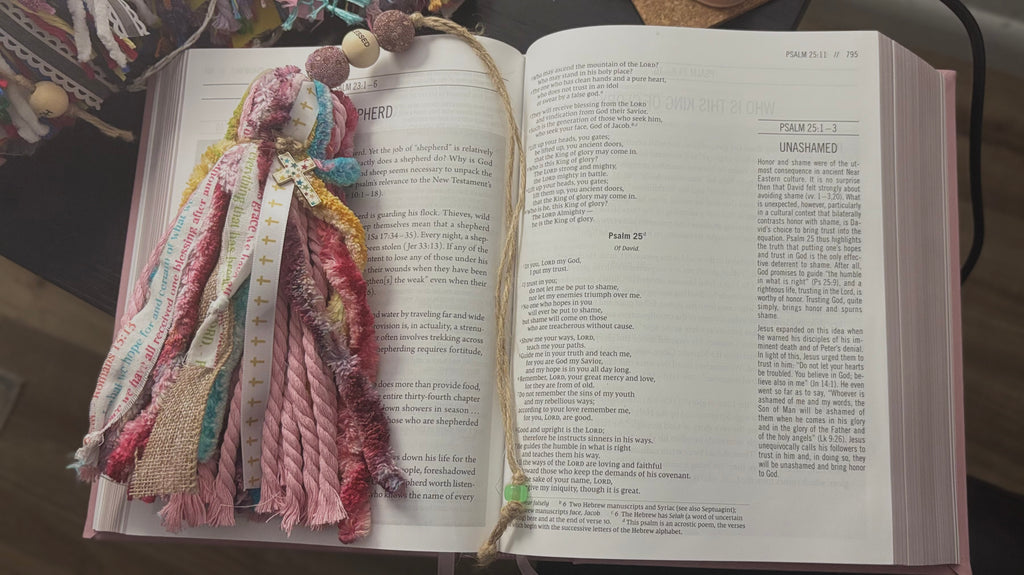 Open book with colorful fabric bookmark on a dark surface