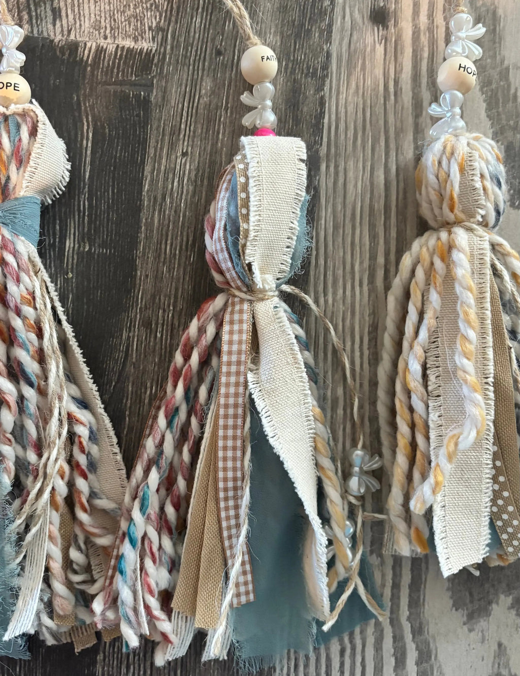 Decorative tassels with braided ribbons hanging against a wooden background