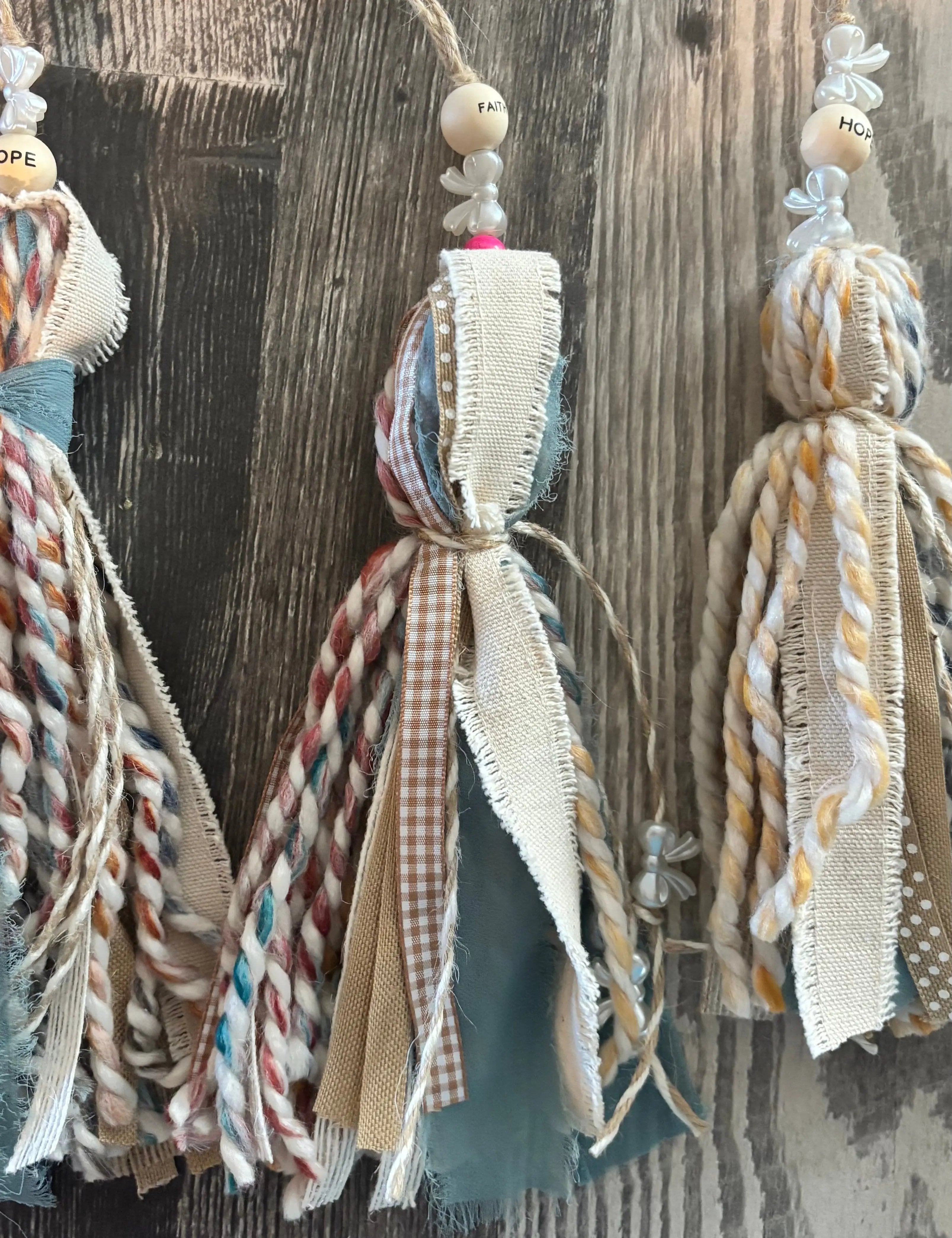 Decorative tassels with braided ribbons hanging against a wooden background