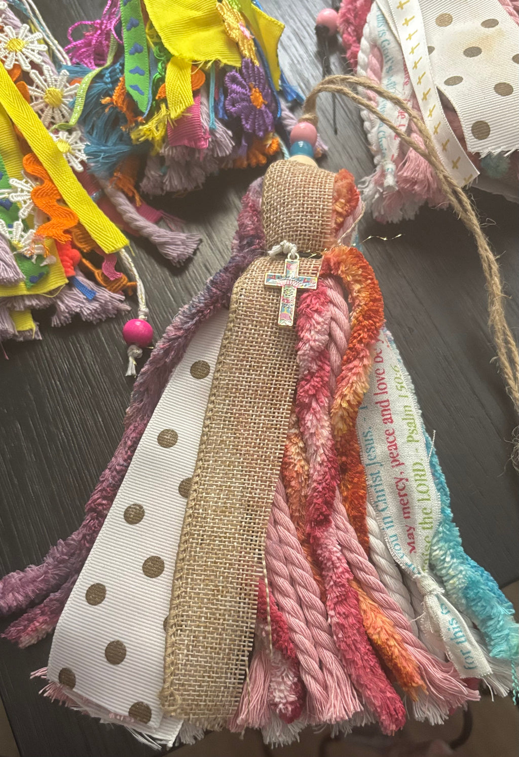 Decorative ribbon with colorful tassels and a cross on a dark surface
