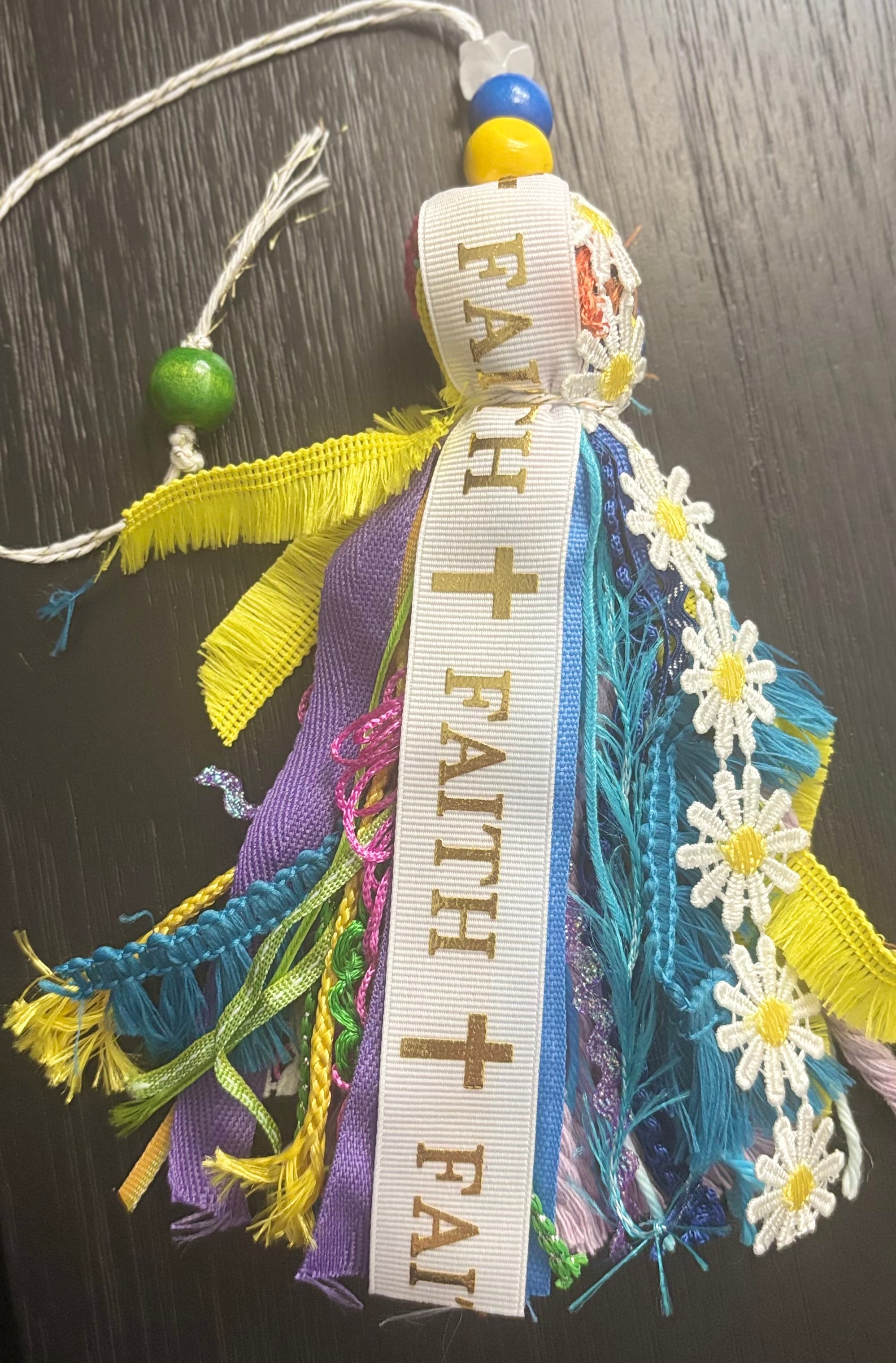 Decorative item with ribbons, beads, and flowers on a dark surface