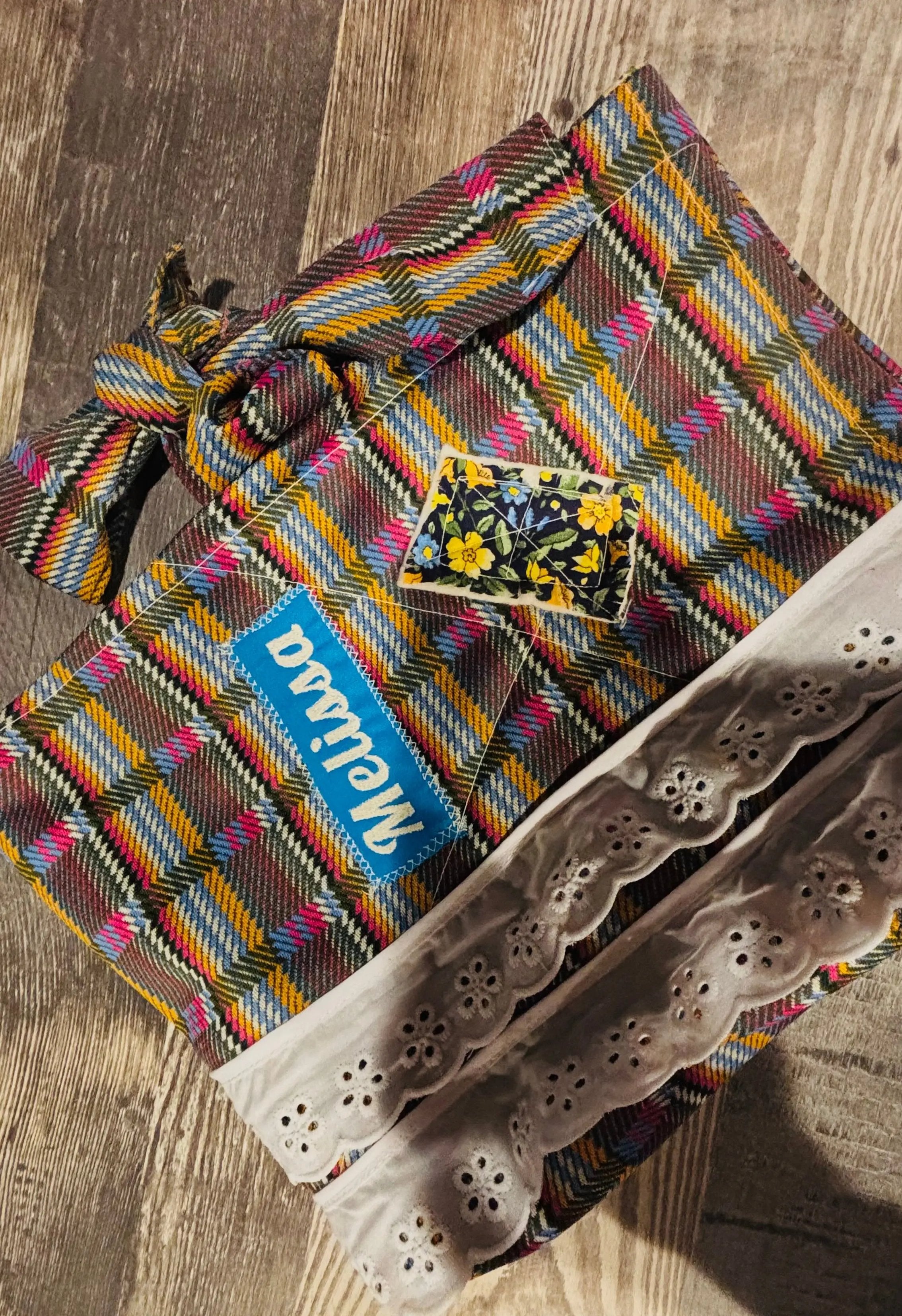 Colorful woven bag with a floral patch on a wooden surface