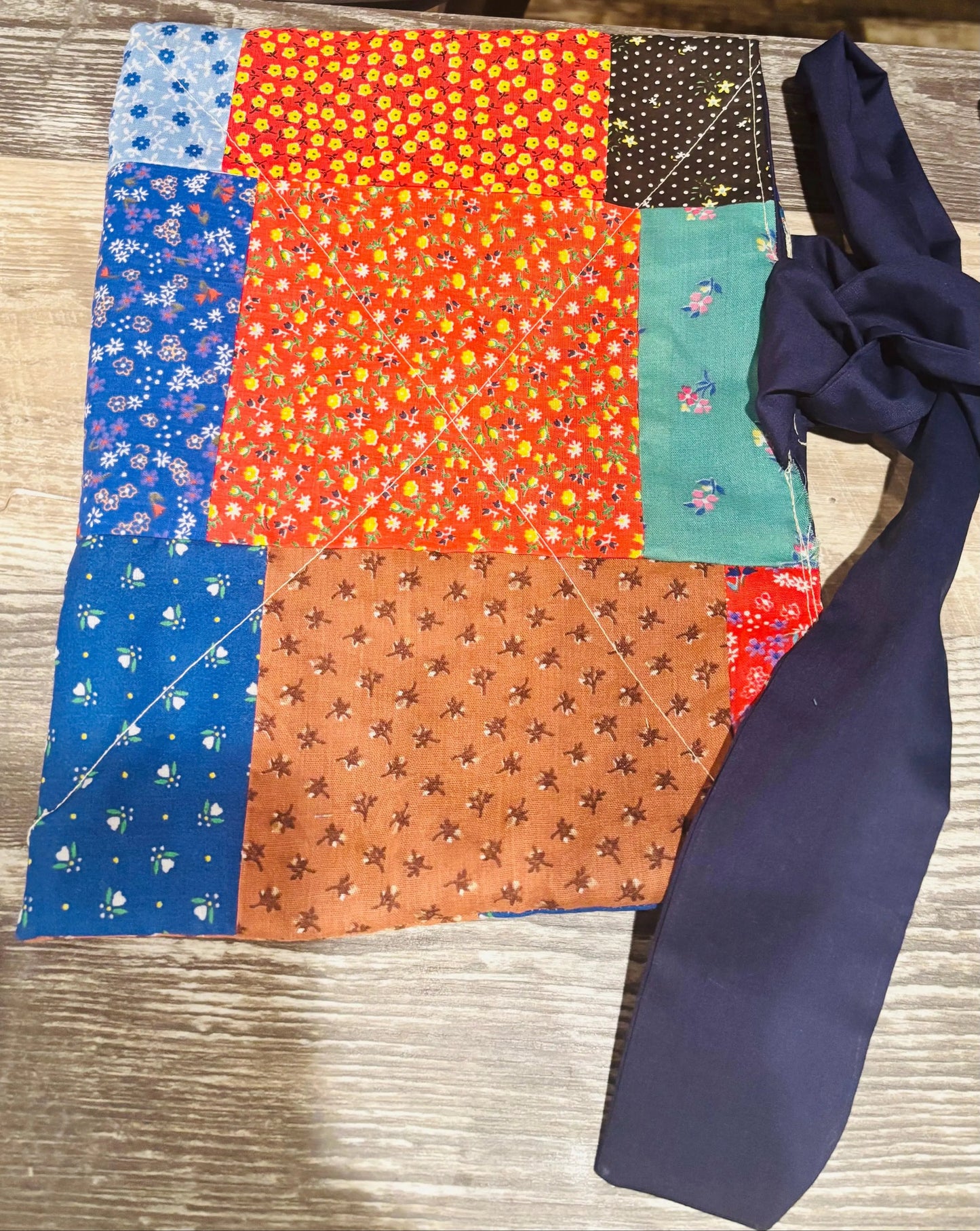 Colorful patchwork fabric with a blue tie on a wooden surface